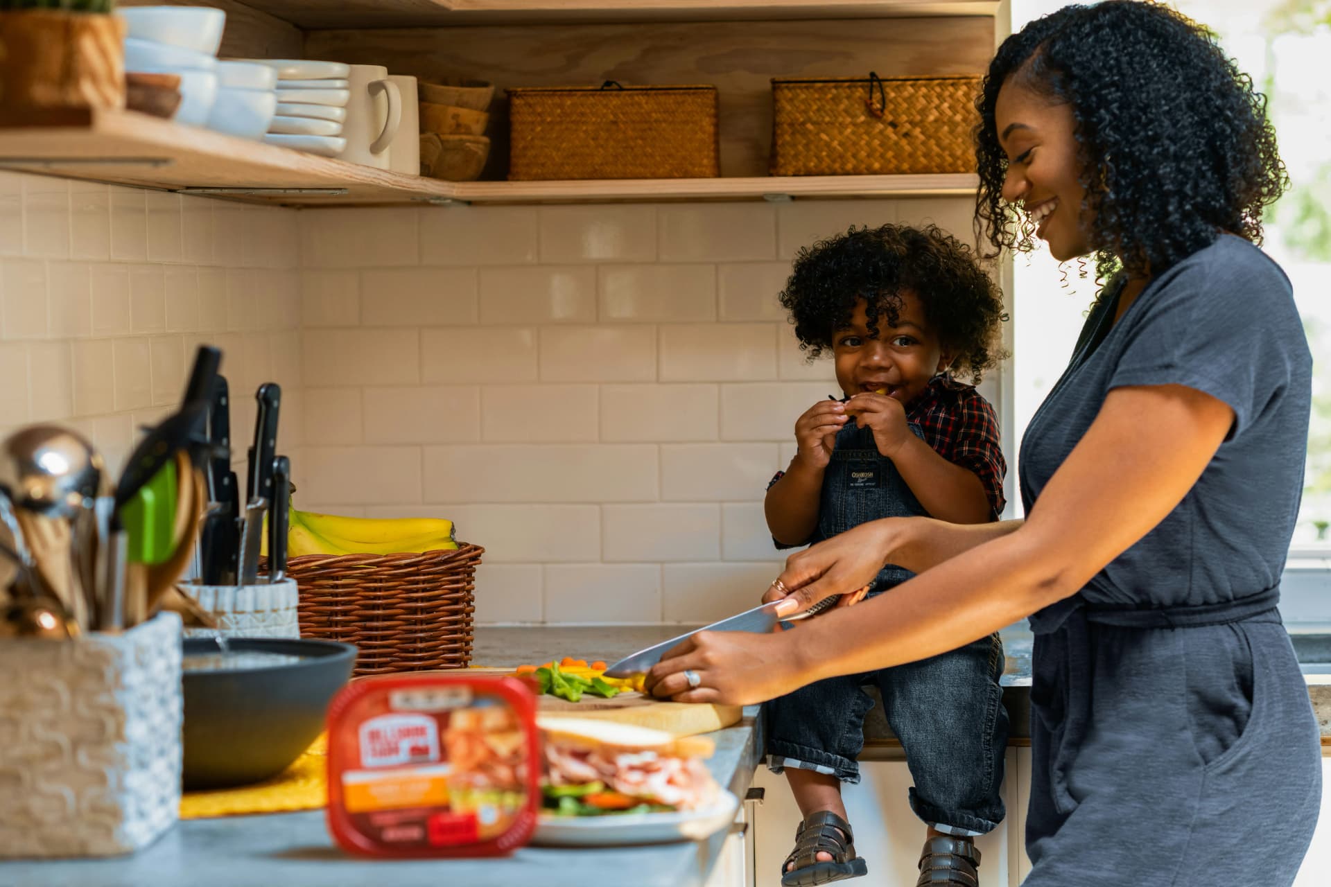 Family or couple laughing together while cooking a meal from a tablet displaying Kitchendary. Warm, lifestyle aesthetic.