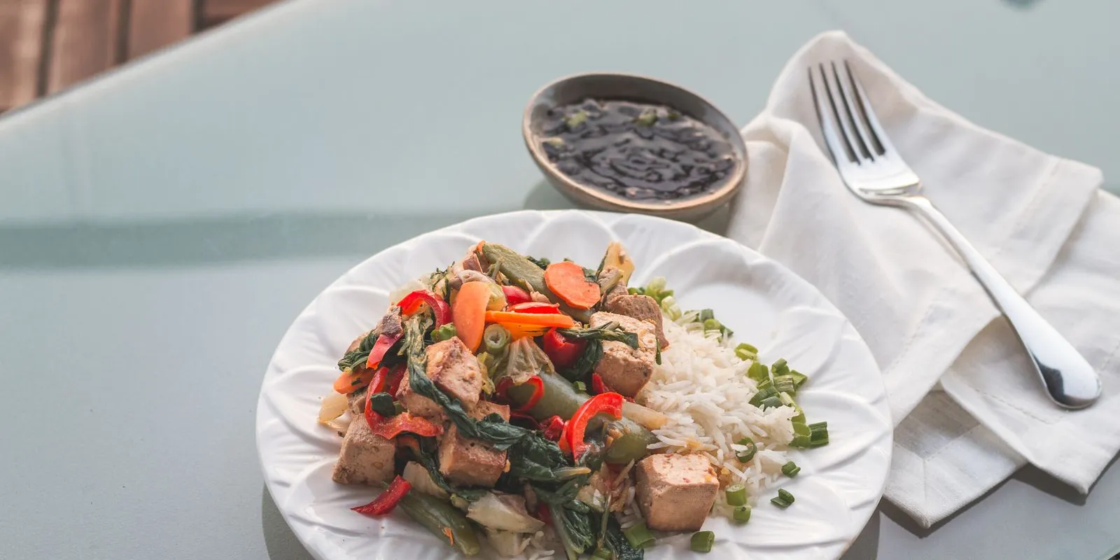 Tofu and vegetable stir-fry with rice on a white plate